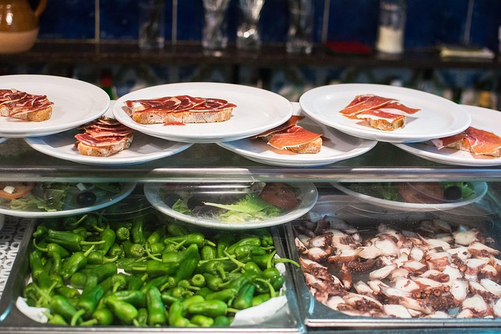 En liten grupp njuter av tapas och vin på en traditionell bar i Madrids historiska centrum, foto 48 | wizardtrip